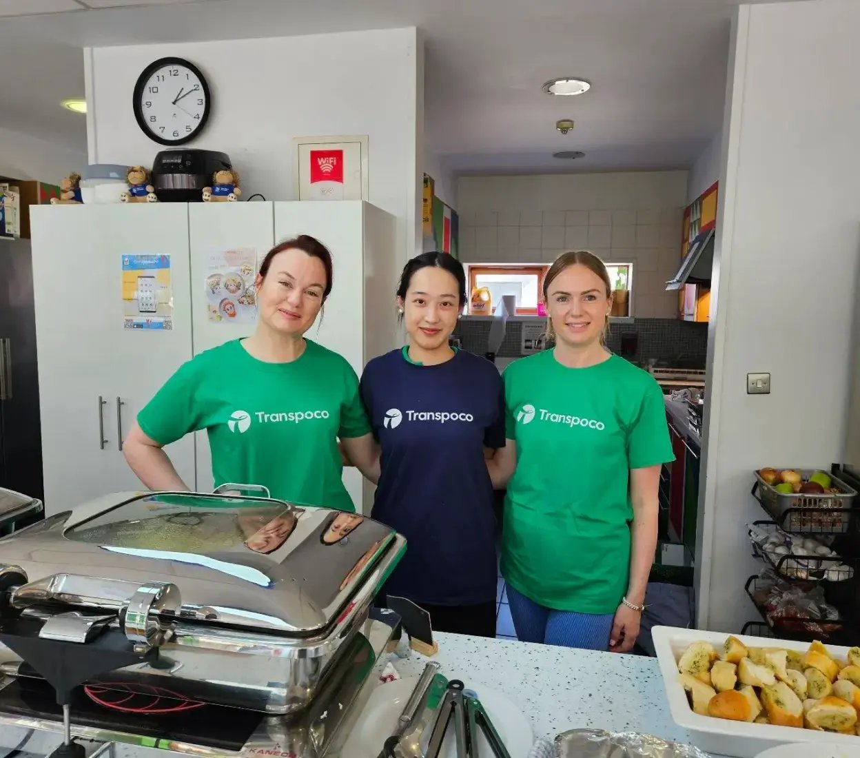 Three smiling Transpoco employees in a kitchen, supporting a local charity