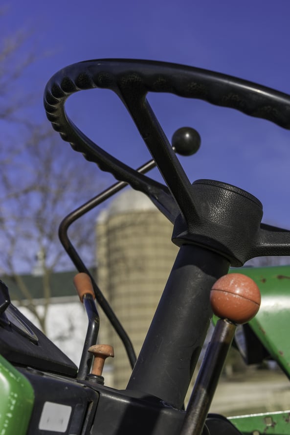 In control on the farm Closeup of steering wheel and shift gears of tractor near silo and outbuilding on a public farm in northern Illinois, USA, on a sunny day in spring