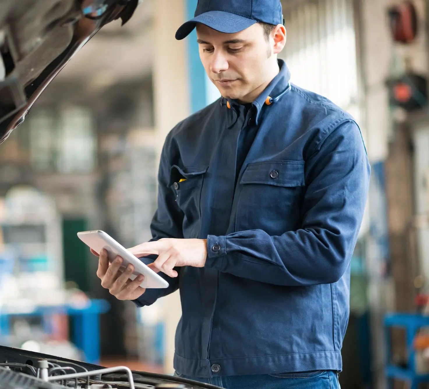 mechanic working on vehicle with device in hands