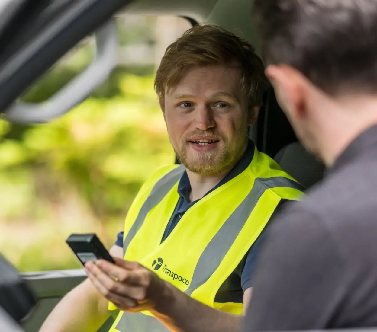 Transpoco employee sitting in the driver's seat of a van, talking to a driver