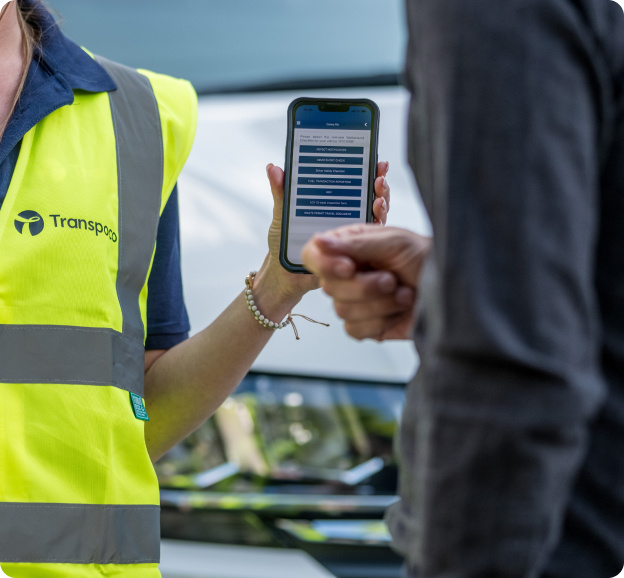 Transpoco employee in a high-vis jacket showing vehicle telematics data to a driver on a smartphone