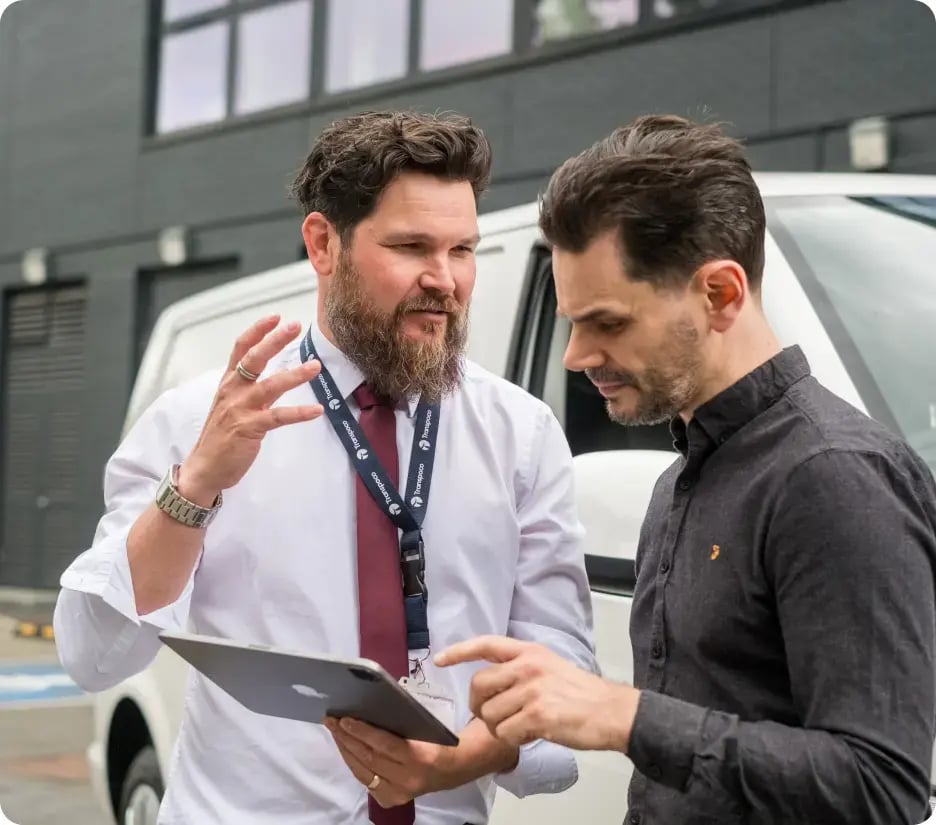 A Transpoco employee holding a tablet, talking to a driver 