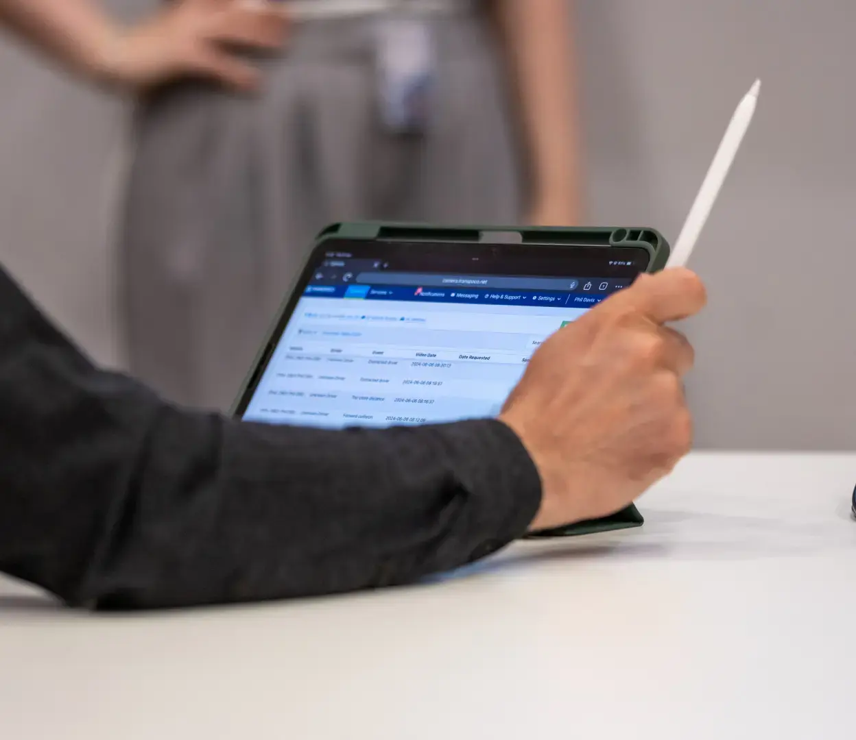 Person holding a stylus, looking at data on a tablet