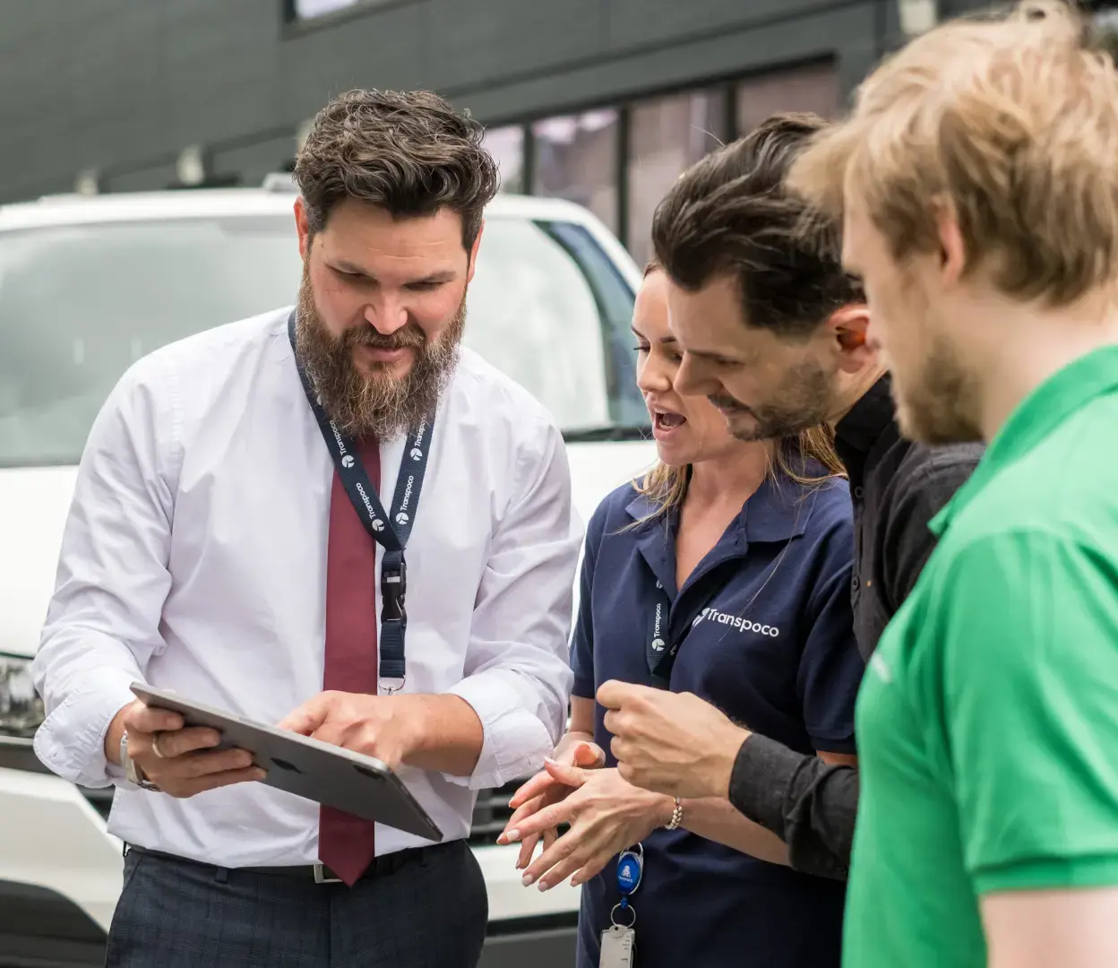 group of people huddling around a tablet