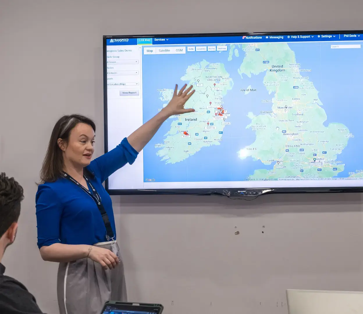 Transpoco employee presenting vehicle tracking data on a large meeting room screen