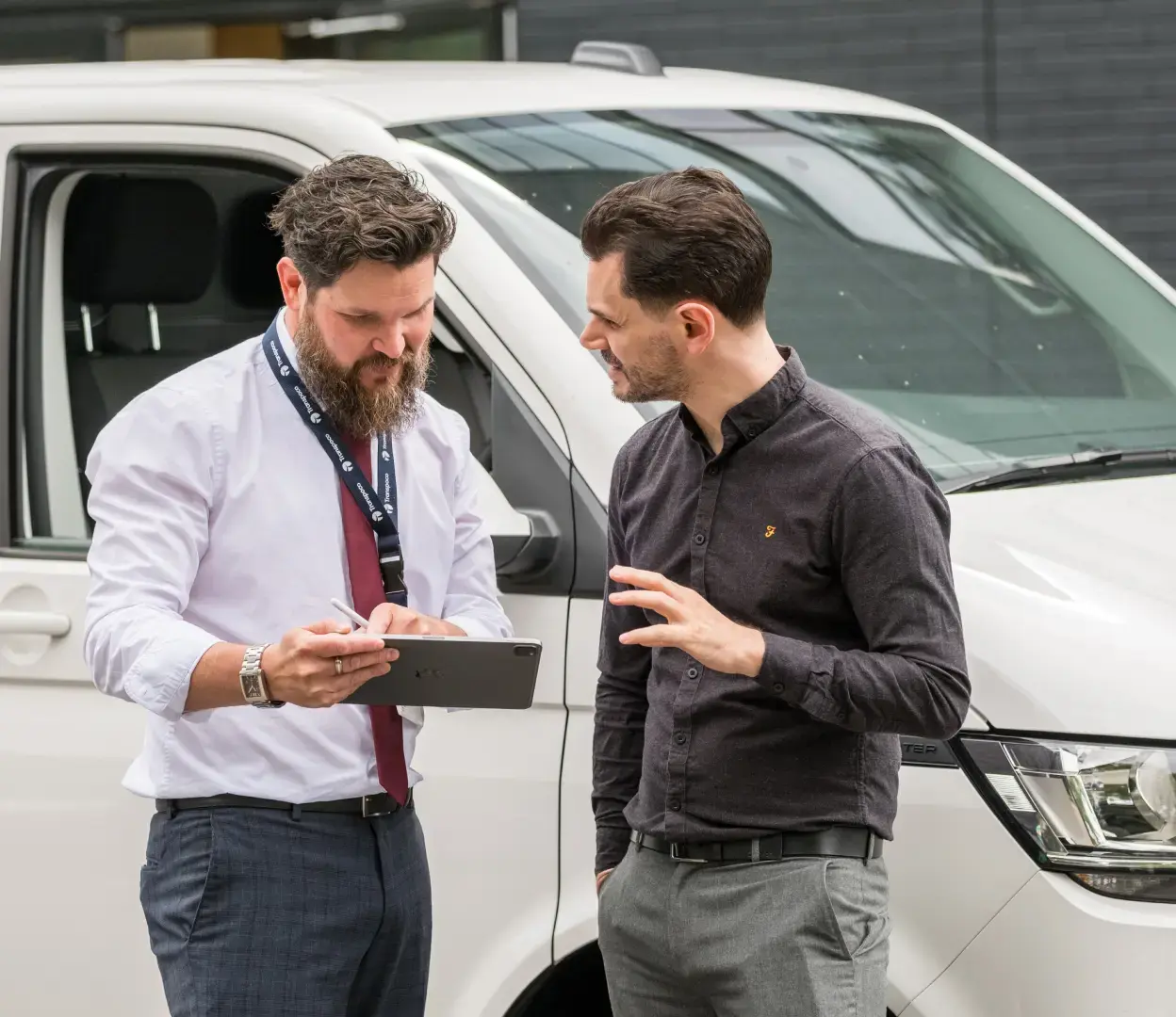 Transpoco employee standing in front of a van, showing a driver in a black shirt data on his tablet