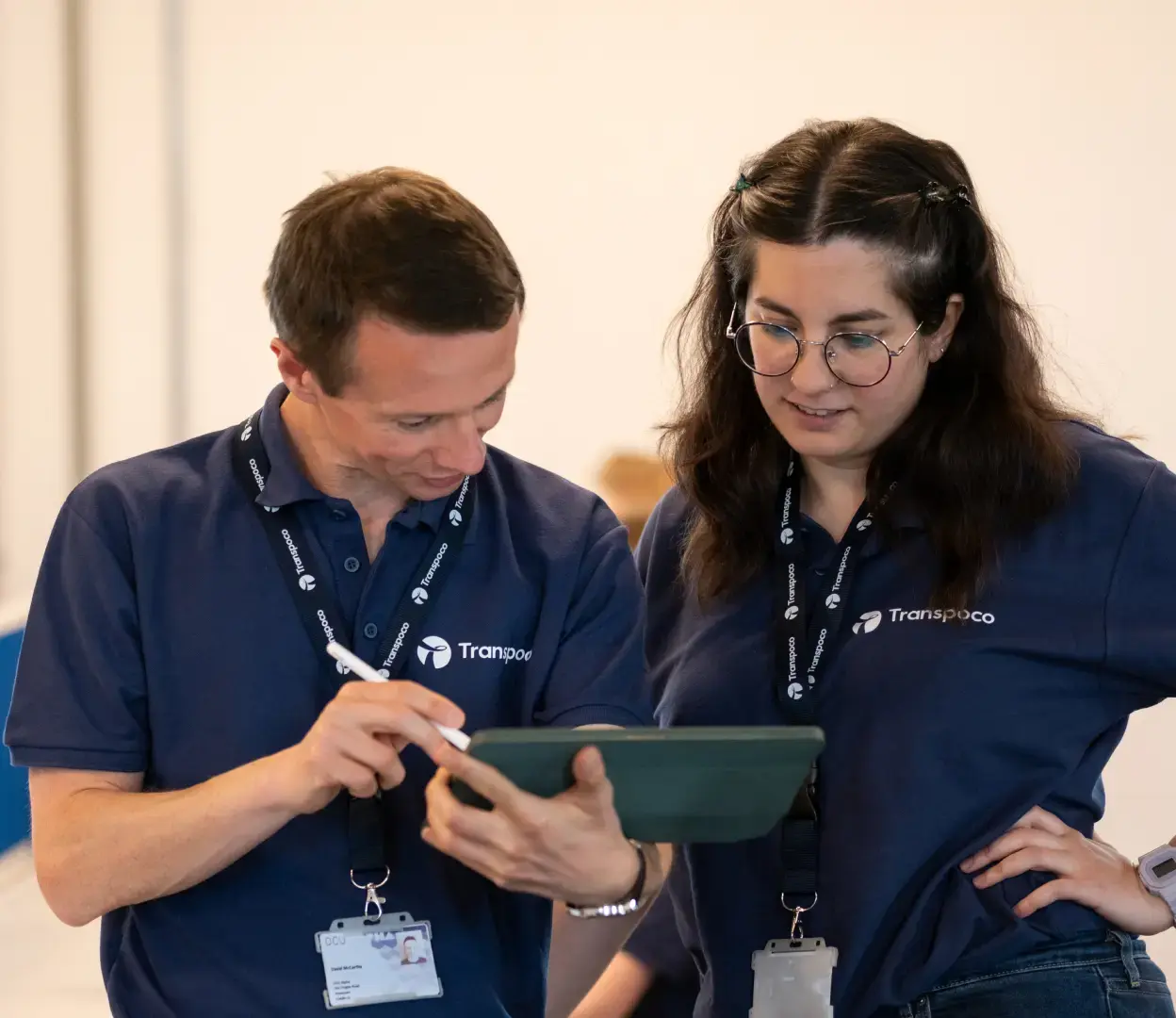 Two Transpoco employees in dark blue shirts reviewing data on a tablet