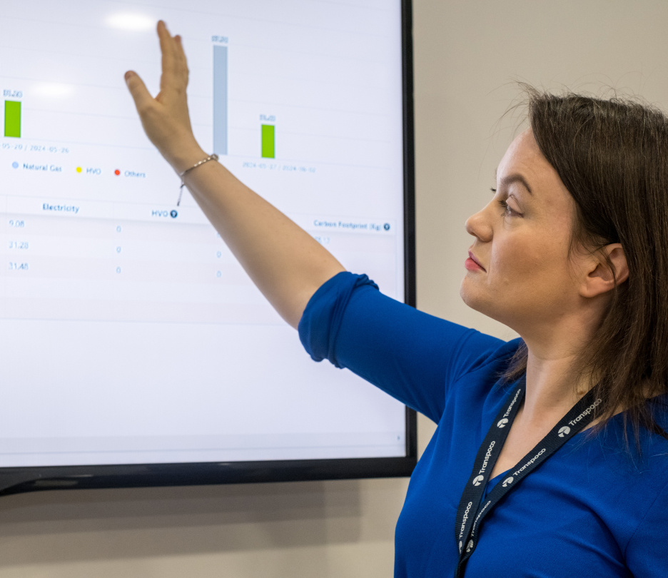 Transpoco employee in a blue shirt presenting data from a large TV screen